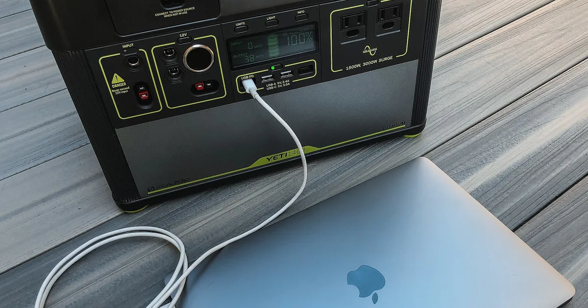 Station d'énergie portable rechargeant un ordinateur portable sur une table en bois pendant une coupure de courant